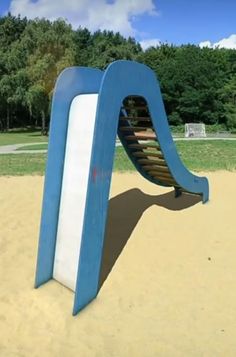 a blue and white sculpture in the sand at a park with trees in the background