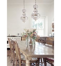 a dining room table with chairs and vases on it's centerpiece hanging from the ceiling