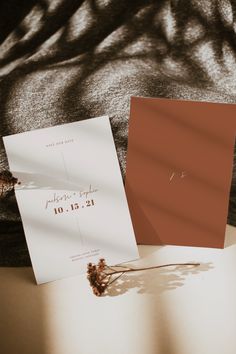 the wedding stationery is laid out on top of an open book, next to a dried flower