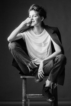 a black and white photo of a woman sitting on a stool