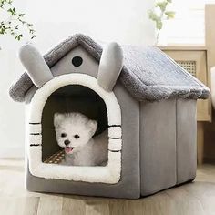 a small white dog in a gray house shaped bed