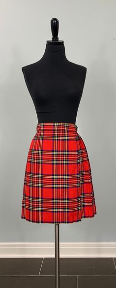 B E S T  F I T S  Suggested Size: 00/0 - Girl's size 10  Please check measurements below to ensure the best possible fit.    D  E  S  C  R I  P  T  I  O  N    *Red, green, black, blue, yellow, and white wrap mini skirt  *Plaid pattern  *Wrap construction  *Black leather straps and metal buckle fasten waistline  *Flat front - pleated back/sides  *Frayed vertical hemline  *Item is not lined  *There is no stretch to the fabric  *Above the knee/knee length  *Possibly a girl's size 10  *1980s - 1990s era    D  E  T  A  I  L  S    * Fabric: 80% Acrylic, 20% Wool  * Care: Dry clean  * Marked Size: 10  * Maker's Label: Lord & Taylor - made in England    M  E  A  S  U  R  E  M  E  N  T  S    (Measurements are taken flat across the front, then doubled when appropriate.)  *Waist: 24"  *Hips: 34"+  *L Red Plaid Skirt Outfit, Mini Skirt Plaid, Plaid Mini Pleated Skirt With Lining, Red And Black Plaid Skirt, Cheap Plaid Red Pleated Skirt, Vintage Pleated Plaid Skirt, Yellow Plaid Skirt, Red Tartan Rara Skirt, Plaid Pleated Mini Skirt