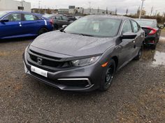 a gray car parked in a lot next to other cars