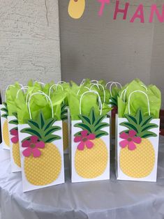 small bags with pineapples on them are sitting on a table in front of a thank you sign