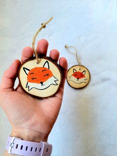 a hand holding a wooden ornament with an image of a fox on it