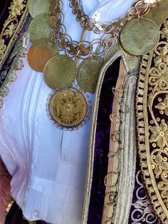 a close up of a woman's clothing with many necklaces on her chest