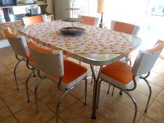 a dining room table with orange and white chairs