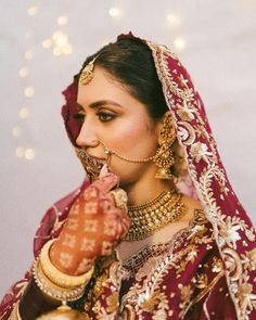 a woman in a red and gold bridal outfit with her hands on her face