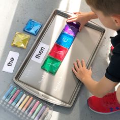 a young boy is playing with colored crayons on a tray and some markers