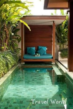 the pool is surrounded by greenery and blue pillows