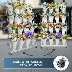 a bunch of white vases with flowers in them on a metal rack next to a sidewalk