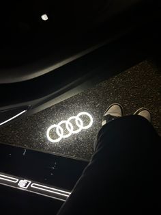 someone is sitting on the floor with their feet up in front of an audi logo