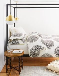 a white bed with black and white comforter in a bedroom next to a table