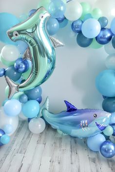 a balloon arch with a dolphin and shark on it, surrounded by blue and white balloons