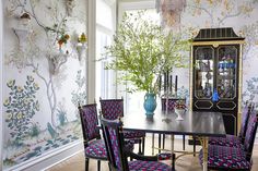 the dining room table is surrounded by chairs and vases with flowers on them, along with wallpaper