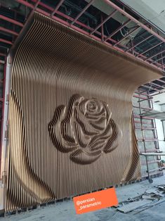 a large metal sculpture with a rose on it's side in front of scaffolding