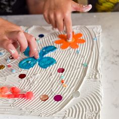 someone is decorating a cake with flowers and butterflies on the frosted icing