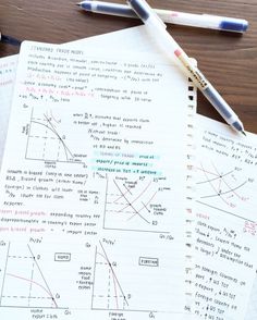 two notebooks with graphs and pens on them