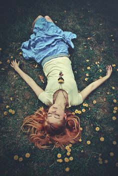 a woman laying on the ground with her head down and eyes closed, in front of yellow flowers