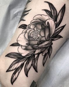 a black and white flower with leaves on the thigh by tattoo artist, amanda lee