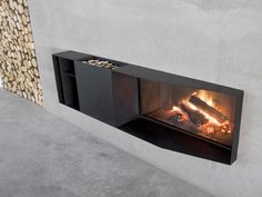 a fire place in the middle of a concrete wall with logs on either side and an open flame