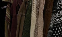 an assortment of sweaters hanging on a rack