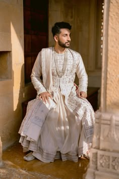 a man in a white outfit sitting down