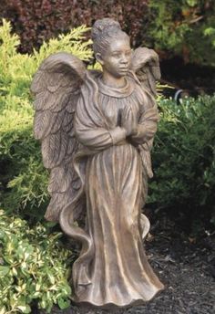 a statue of an angel standing next to bushes