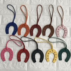 six different colored horseshoes are hanging on a brick wall and one is black, white, red, yellow, green, blue, pink