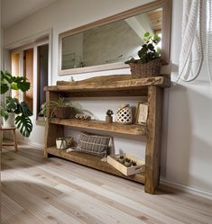 a wooden shelf with potted plants on it in front of a mirror and window