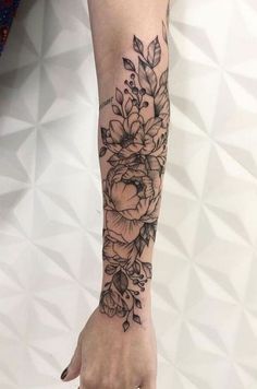 a woman's arm with flowers and leaves tattooed on the left side of her arm