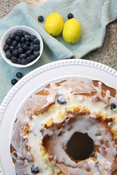 a blueberry bunt cake on a white plate with lemons and blueberries