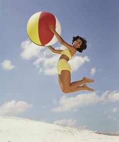 a woman jumping in the air with a beach ball