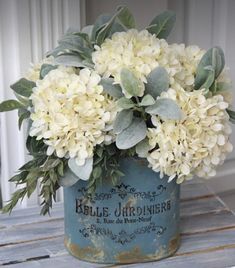 a blue bucket filled with white flowers on top of a wooden table