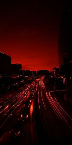 the city is lit up at night with long exposure and red light in the background