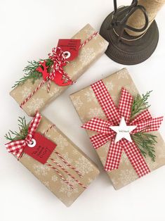 three wrapped presents sitting next to each other on top of a white table with a bell