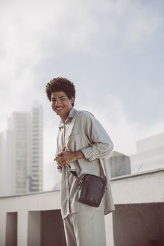 a man standing on top of a roof holding a black bag and smiling at the camera