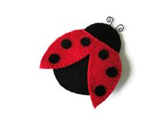 a red and black ladybug brooch sitting on top of a white surface