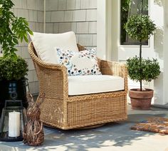 a wicker chair sitting on top of a patio next to a potted plant