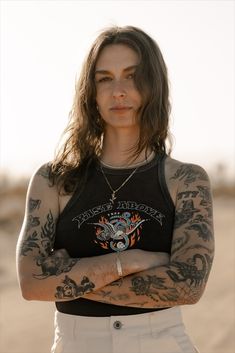 a woman with long hair and tattoos on her arms