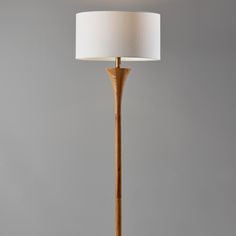 a wooden floor lamp with a white shade on the top and bottom part of it