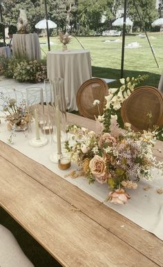 a table with flowers and candles on it at an outdoor wedding reception in the park