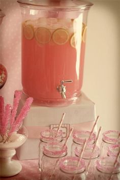 there is a pink machine and many glasses on the table with strawberries in them