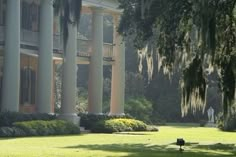 a large building with columns and trees in front of it, surrounded by green grass