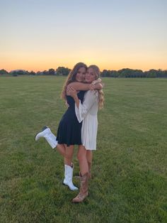 two women hugging each other in the middle of a field