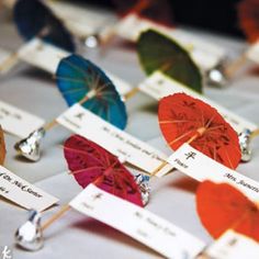 several colorful umbrellas with name tags attached to them sitting on top of a table