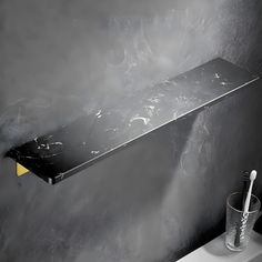 a black and white marbled shelf next to a toothbrush holder in a bathroom