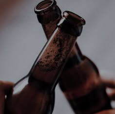 two empty beer bottles being held by someone's hand