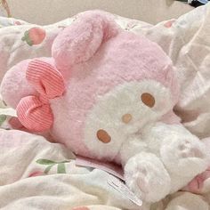 a pink hello kitty stuffed animal laying on top of a white bed covered in blankets