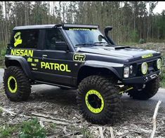 a black and yellow jeep parked on the side of a road in front of trees